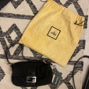 Fendi Baguette Väska - Från A Retro Tale där den blivit autenserad av deras experter. Tyckte inte riktigt om ”tyget” som är lite som ull, men tiden för att lämna tillbaka den hade passerat så säljer vidare. Ej använd, alla taggar sitter kvar och äkta fendi dustbag medföljer.