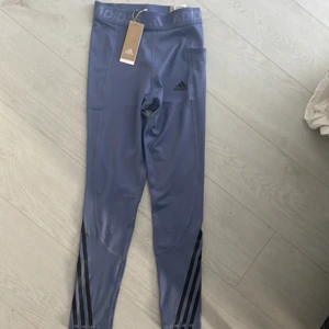 Adidas tränings tights - Jätte fina, helt nya adidas träningstights. Lappen sitter kvar. Älskar färgen men kunde tyvärr inte ha dem. Fina detaljer plus en ficka vid sidan. Köptes för 450 kr.