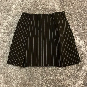 Kjol från Ginatricot  - En svart kjol med vit tunna ränder i storlek xxs från Ginatricot. Bra skick 