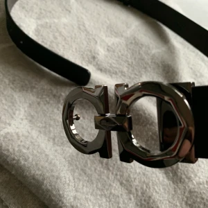 Salvatore Ferragamo bälte - I princip helt nytt ferragamo bälte i Svart/brunt. (Första bilden är från när jag fick hem det). Size 85 men sitter lite åt det större hållet. Hålslagare följer med om det skulle vara för stort. Inga hål slagna än. Skriv för mer info eller bilder. 