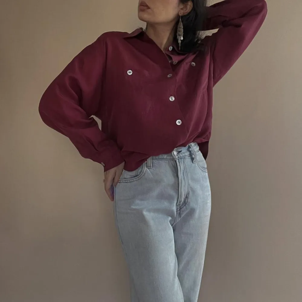 Vintage Oversized Silk Burgundy Blouse with Mother of Pearl Buttons. 2 Frontal Pockets. 100% Silk. Dry Clean Only.   Flatlay Measurements 75cm Length 56cm Sleeve 49cm Shoulder to Shoulder 114cm Chest. Toppar.