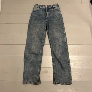 VANJA Vida high waist jeans med croppat ben - Mjuka och bekväma jeans i blå tvätt med hög midja och vida, croppade ben med fransad kant.  Justerbar midja med resår Croppade och vida ben med fransad kant Femficksmodell Dragkedja och knapp Stadig bomullsdenim