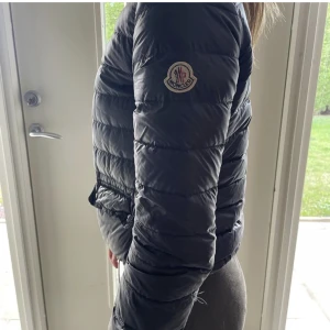 Moncler Lans - En perfekt jacka! Ha under kappan när det är kallt ute eller över tröjan en sommarkväll! Köpt på NK för 7 år sen, modellen heter Lans. Storlek 14 år, passar mig som är 22 år och 160 cm. Tre små ”fimp” hål som nog är billigt och enkelt för skräddaren. 