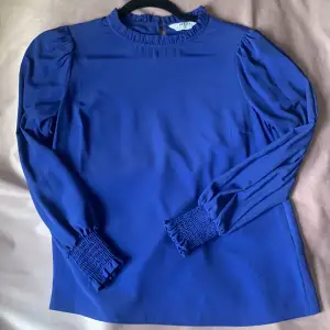 Blå blus i storlek 34 med volangkrage, använd ett fåtal gånger.