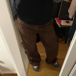 Low Rise cargo pants - Super trendiga cargo pants från Urban outfitters! Långa på mig som är 165. Byxorna har låg midja och  mörkbrun färg. Funkar för både dig som har 36/38, beror på hur du vill de ska sitta. Original pris: 750, säljs för lite mindre än halva! Aldrig använda. 
