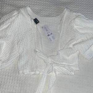 Vit tröja med snörning där bak, köpt från Gina Tricot, köpt för 249kr.  Lappen sitter kvar så aldrig använd.  Strl XL men passar L  Pris kan diskuteras 