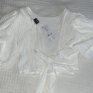 Tröja med snörning  - Vit tröja med snörning där bak, köpt från Gina Tricot, köpt för 249kr.  Lappen sitter kvar så aldrig använd.  Strl XL men passar L  Pris kan diskuteras 