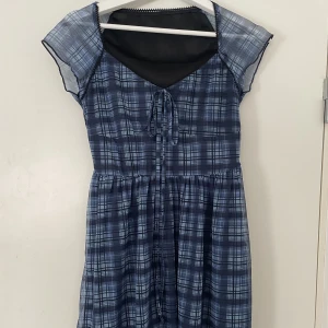 Blå rutig klänning - Blå rutig klänning, ganska kort. Passar tyvärr inte mig. Köpt här på plick. Ett svart lager och sen blått mesh tyg utanpå. 