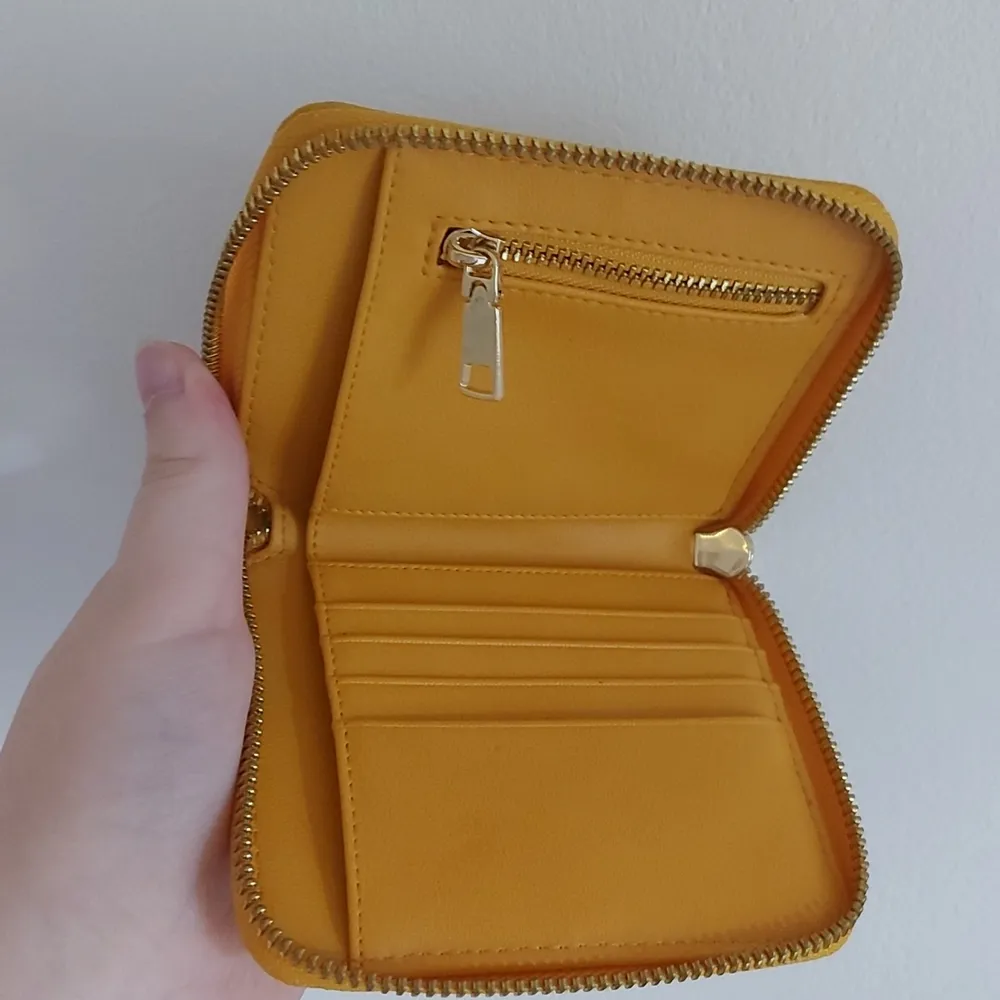 En gul plånbok med dragkedja. Det finns plats för kort, lösa sedlar och mynt. (I nytt skick) pris kan diskuteras. Väskor.