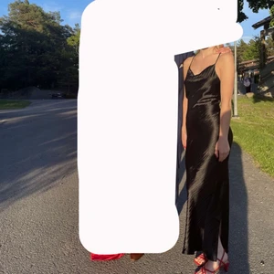 Satinklänning  - Svart satinklänning använd 1 gång. Den har en liten slits som man ser på bild 1. Superfin i ryggen och man kan sätta snörena på olika sätt. 