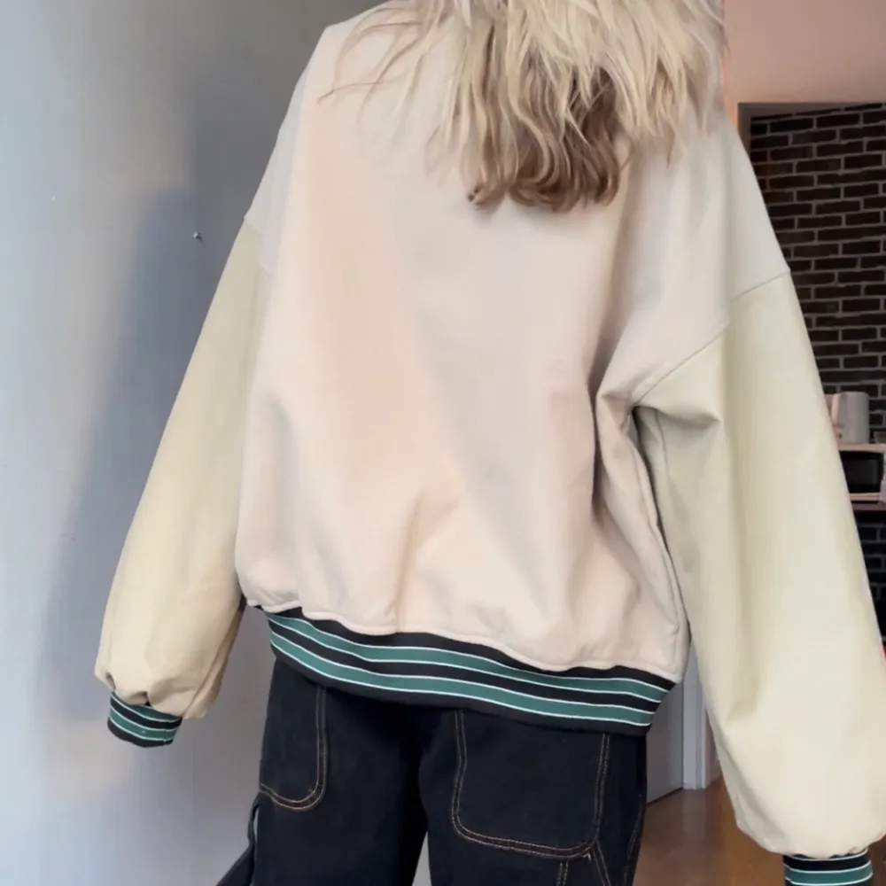 Beige college jacka från Boohoo med fake läder på armarna. Superbra kvalitet, däremot har knappen näst högst upp trillat av. Jag är 160 cm lång, och som ni ser är jackan för stor för mig.  Storlek 34, längd: 63 cm, armlängd mätt från axeln: 66 cm. Jackor.