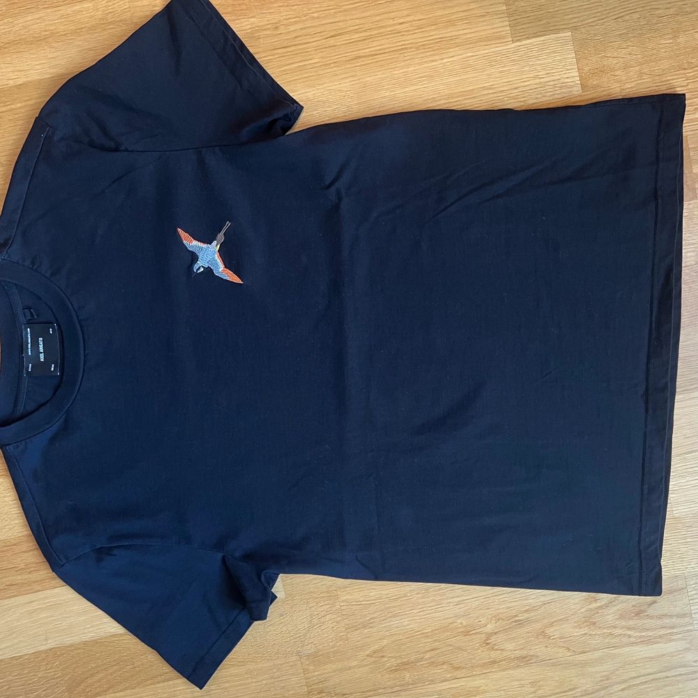 En svart T-shirt från Axel Arigato i strl. XS oanvänd i nyskick. Tryck med fågel. Köparen betalar frakten. . T-shirts.