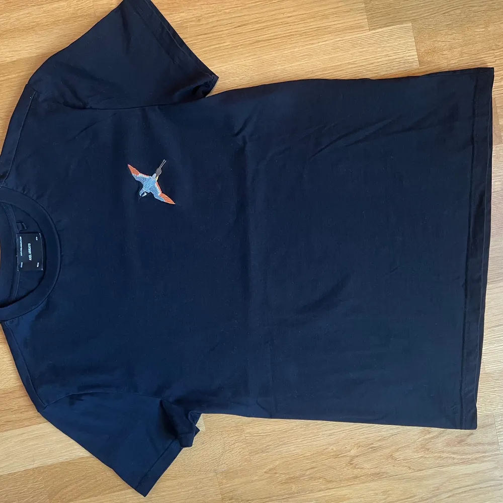 En svart T-shirt från Axel Arigato i strl. XS oanvänd i nyskick. Tryck med fågel. Köparen betalar frakten. . T-shirts.