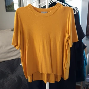 Cos stickad t-shirt - Finstickad t-shirt med veckad rygg som ger ett fint fall. Senapsgul i gott skick. 55% bomull 45% viskos