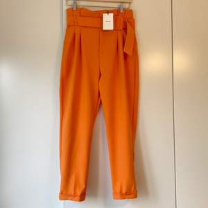 Helt nya aprikosfärgade byxor från Bershka med prislappen kvar. Snyggt skärp i midjan. Storlek 40/12.