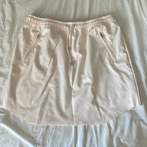 Kjol nakd - Ljus beige/rosa skinnskjorta från nakd. Knappt använd men har små fläckar från att ha legat med ett par svarta skinnbyxor därav priset. Storlek 42. Frakt tillkommer 