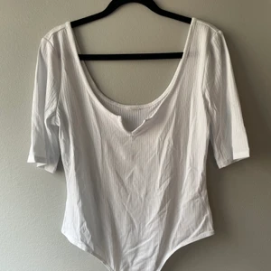 Body, Medium - Vit body, medium. Oanvänd. Köpte under graviditet, klippte bort lappar men använde aldrig. Storlek medium. Knappar där nere som man kan knäppa ihop så den sitter på plats. 