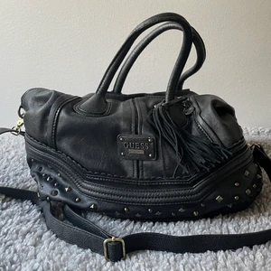 Guess väska - Skolböcker/ dator får plats, emblemet något rostigt, blommig insida. Den är äkta men väldigt använd, har ej heller kvitto, köpte i Prag för kanske 7 år sedan i Guessbutiken.