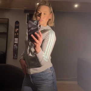 Adidas tröja  - Grå adidas tröja med turkosa ränder. Står storlek 152 i tröjan men passar mig som är XS-S