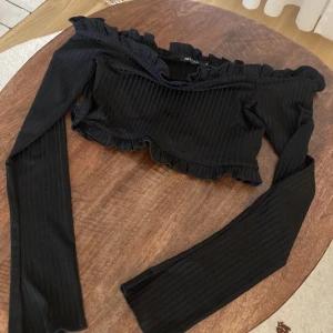 Svart crop topp offshoulder S - Svart ribbad offshoulder topp i storlek S från Nelly. Säljer pga att den är för stor för mig. Finns i Farsta 