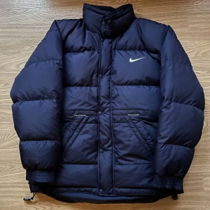 Nike Vinterjacka storlek S - Riktigt snygg vintage vinterjacka i dun från tidigt 2000-tal! Den är i Storlek S, osäker på om det är dam eller herr men den passar unisex. 10/10 skick, Inget att anmärka på. Buda från 850kr eller köp direkt för 1090kr!