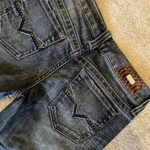 Raka lågmidjade jeans Guess - Lågmidjade jeans med raka lätt utsvängda ben. Passar som storlek S i en urtvättad blå färg! Jättefina bakfickor och glitterdetaljer. 39 cm tvärs över midjemått när de ligger platt. Passar i längd på mig som är runt 165. KÖP DIREKT FÖR 400 kr eller buda💓