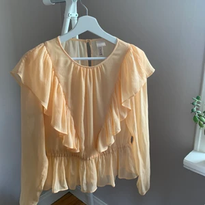Persikofärgad blus med volanger från H&M - 🍑 Persikofärgad blus med volanger🍑 Supersöt blus från H&M i storlek 38 som aldrig använts av mig. Hoppas innerligt den hittar ett nytt hem där den får bäras flitigt.  SKICKAS med postnords fraktpåse för 63kr, önskas spårbart tillkommer det.