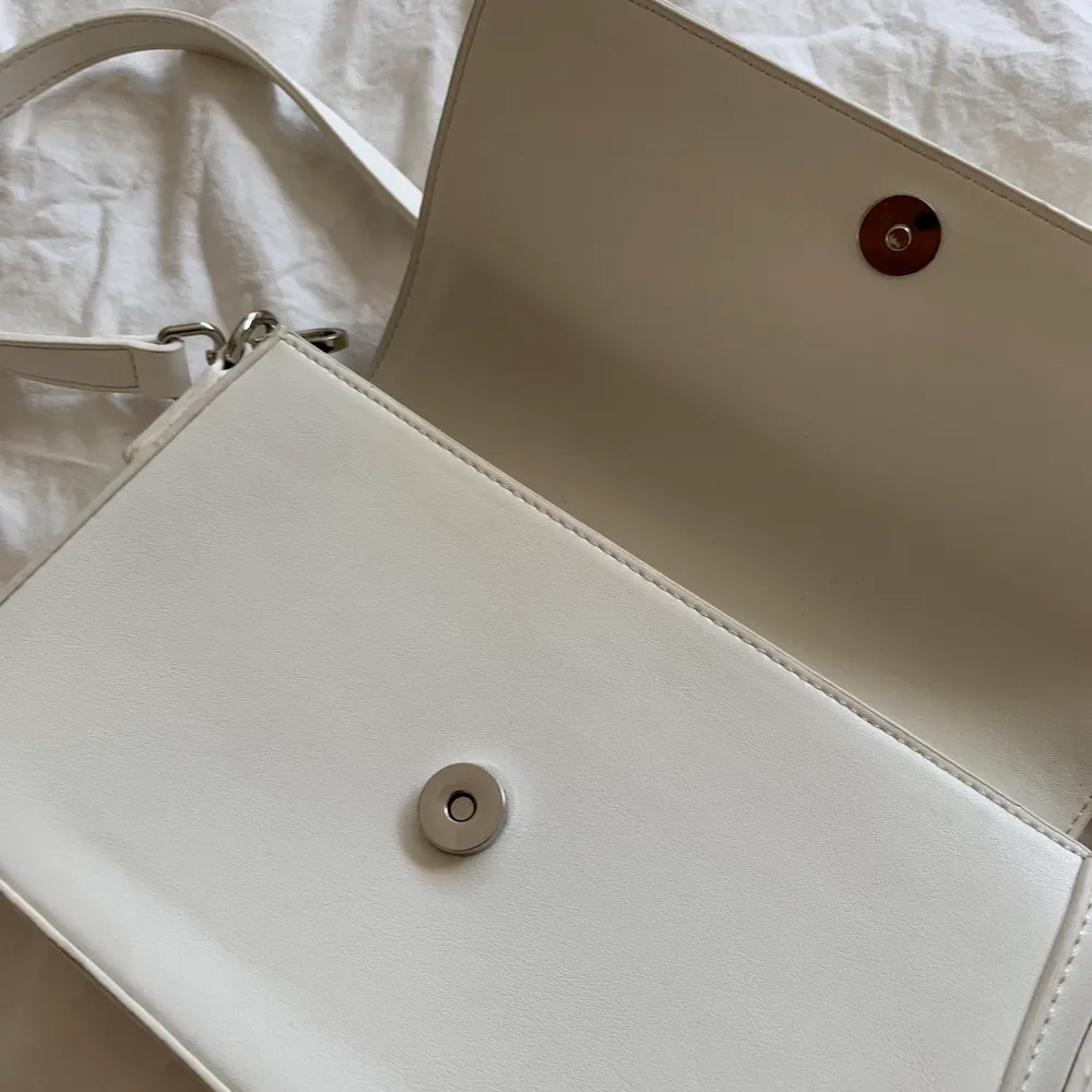 Jättefin vit handväska från Åhléns endast använd en gång på studenten, säljer pga kommer ej till användning.  Den har ett innerfack med dragkejda. Väskor.