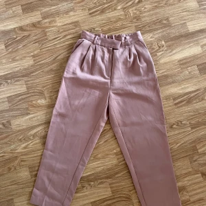 Snygga kostymbyxor  - Säljer dom här snygga kostymbyxorna i lite beige/rosa färg då dom tyvärr inte kommer till användning. Har använts någon enstaka gång så de är i mycket fint skick! 