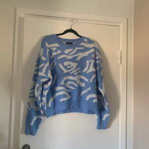 En blå sweatshirt med vitt mönster i storlek M.