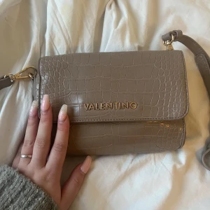 VALENTINO VÄSKA - Säljer min suuper fina Valentino by Mario valentino crossbodybag, den är i väldigt bra skick. Den är lite mer beige grå i verkligheten. Köpt för cirka 900kr för 2 år sedan typ,  Skriv för fler bilder eller vid frågor  ❤️‍🔥❤️‍🔥❤️‍🔥