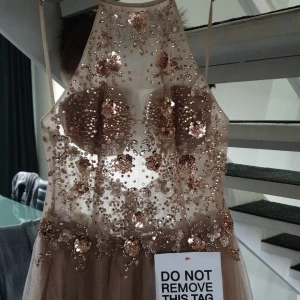 Lyxig klänning från Mascara  - Helt ny klänning från märket Mascara. Köpt från Zalando.  Klänningen sitter mycket fint då överdelen är av tyll genomskinligt med handsydda paljetter. Bar rygg där paljetterna fortsätter nedtill.  Undrdelen är av tyllkjol med slits. I färgen bege. 