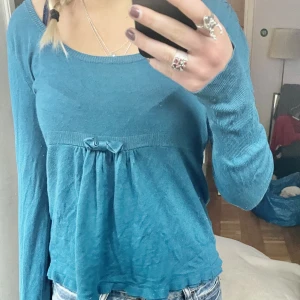 Långärmad tröja - En finstickad tröja med resår och rosett i midjan. Färgen syns bäst på första bilden! Passar från storlek XS-M beroende på hur man vill att den sitter