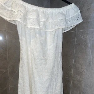 Vit klänning - Vit ”off shoulder” klänning, med blommönster. Bra skick. Använd en gång. Storlek S. Liten i storleken. 