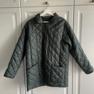 Quiltad jacka - En lättfodrad quiltad jacka. Färgen är varmt mörkgrön. Både dragkedja och knappar🌳