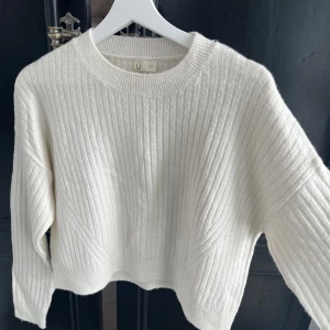 Vit stickad tröja - Fin vit stickad tröja. Är några år gammal och använt en del men inget som syns. Hyfsat kort i modellen.