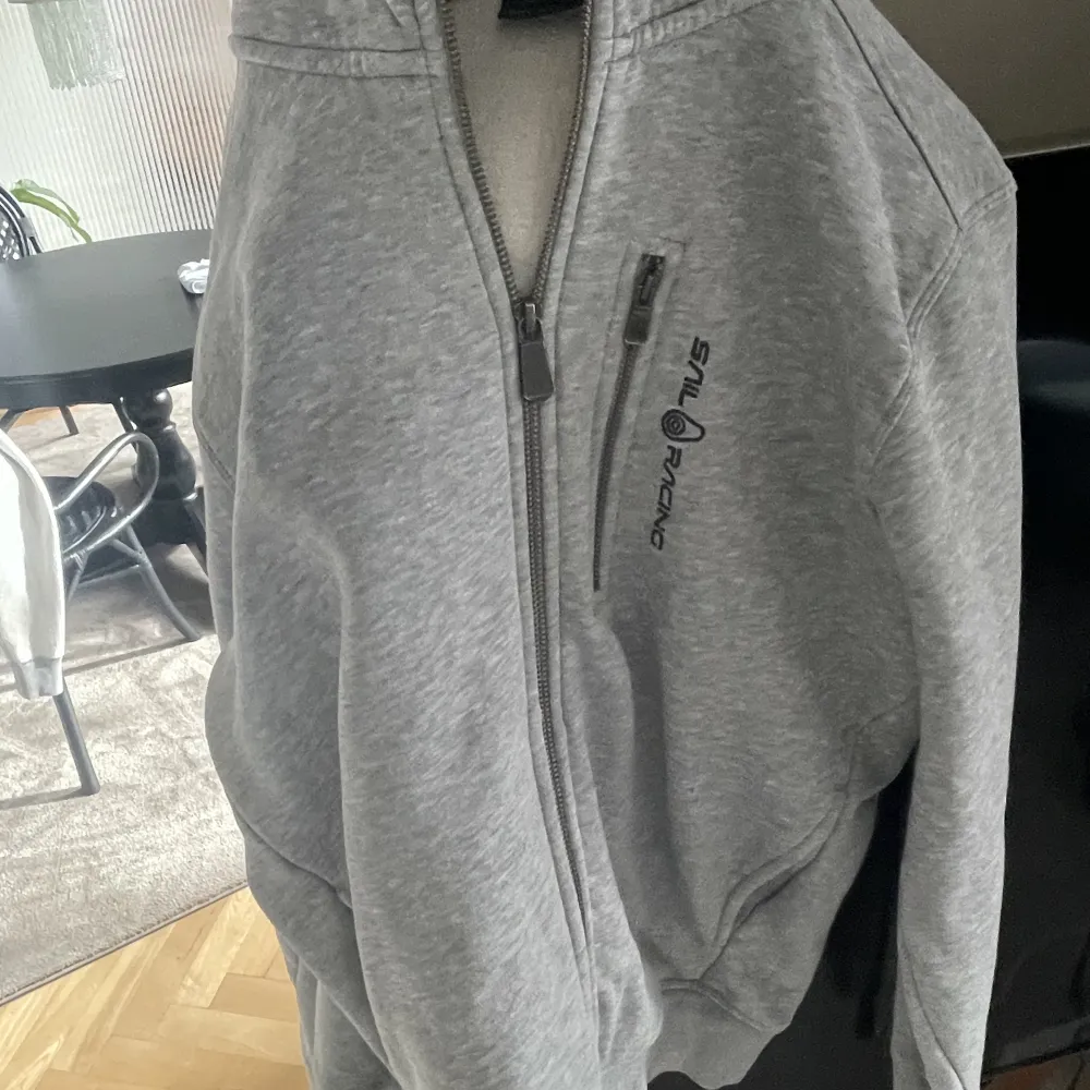 En grå Sail Racing zip hoodie i bra skick. Köpte för ett år sedan och har knappt användt den. Dragkedjan funkar utmärkt och inga fläckar finns överhuvudtaget.. Tröjor & Koftor.