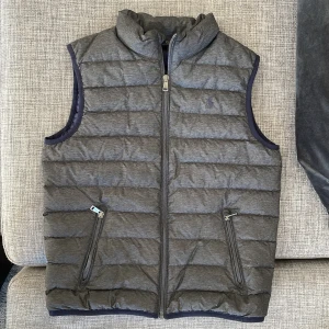 POLO Ralph Lauren dunväst strl 10-12år (M) - Jättefin grå väst med blått foder från POLO Ralph Lauren, junior 10-12år  Inköpt på Kids Brand Store 2021