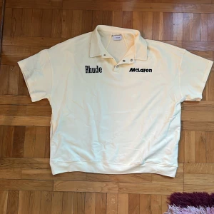 Rhude x McLaren polo beige  - Rhude x McLaren polo i XL, knappt använd men har ett hål i nacken därav priset. Nypris ca 5000kr, senaste som såldes jag hitta online såldes för 1000. Sitter ganska stort t.o.m för XL men den ska vara oversized