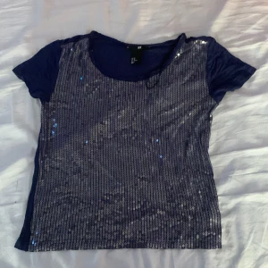 T-shirt med paljetter  - En fin T-shirt med paljetter där fram. Använd en gång. Är i bra skick utan synliga defekter. Storlek xs 