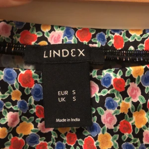 Blank, kort, blommig satinkjol  - Säljer en kort kjol i stl S från Lindex.  Stretchiga i midjan.  100% polyester och i princip skrynkelfri.  Jättefint skick. 