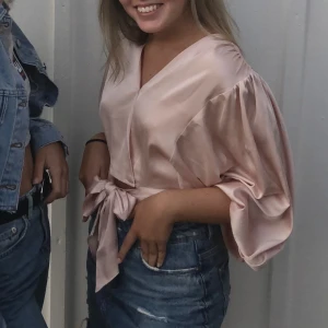 Rosa sidentopp, storlek XS - Jättefin ljusrosa sidentopp från Bikbok i storlek XS! Skulle säga att det även passar en S. Knappen längst ner går inte att stänga men tack vare bandet du knyter till en rosett fungerar tröjan utmärkt ändå!! Ballong-armar som gör tröjan mer speciel!