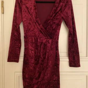 Vinröd klänning - Vinröd klänning, urringad, längd till knäna.