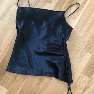 Festtopp - Svart festlinne i satin med dragsko på ena sidan. Aldrig använd, prislappen är kvar. Från BOHOO. Skickas med brev med möts upp :) 