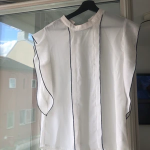 Vit blus storlek S - Fin elegant blus i storleken S med svarta sömmar som detalj✨ fin att ha både vit bralette eller ett linne under till✨ liten fläck på kragen