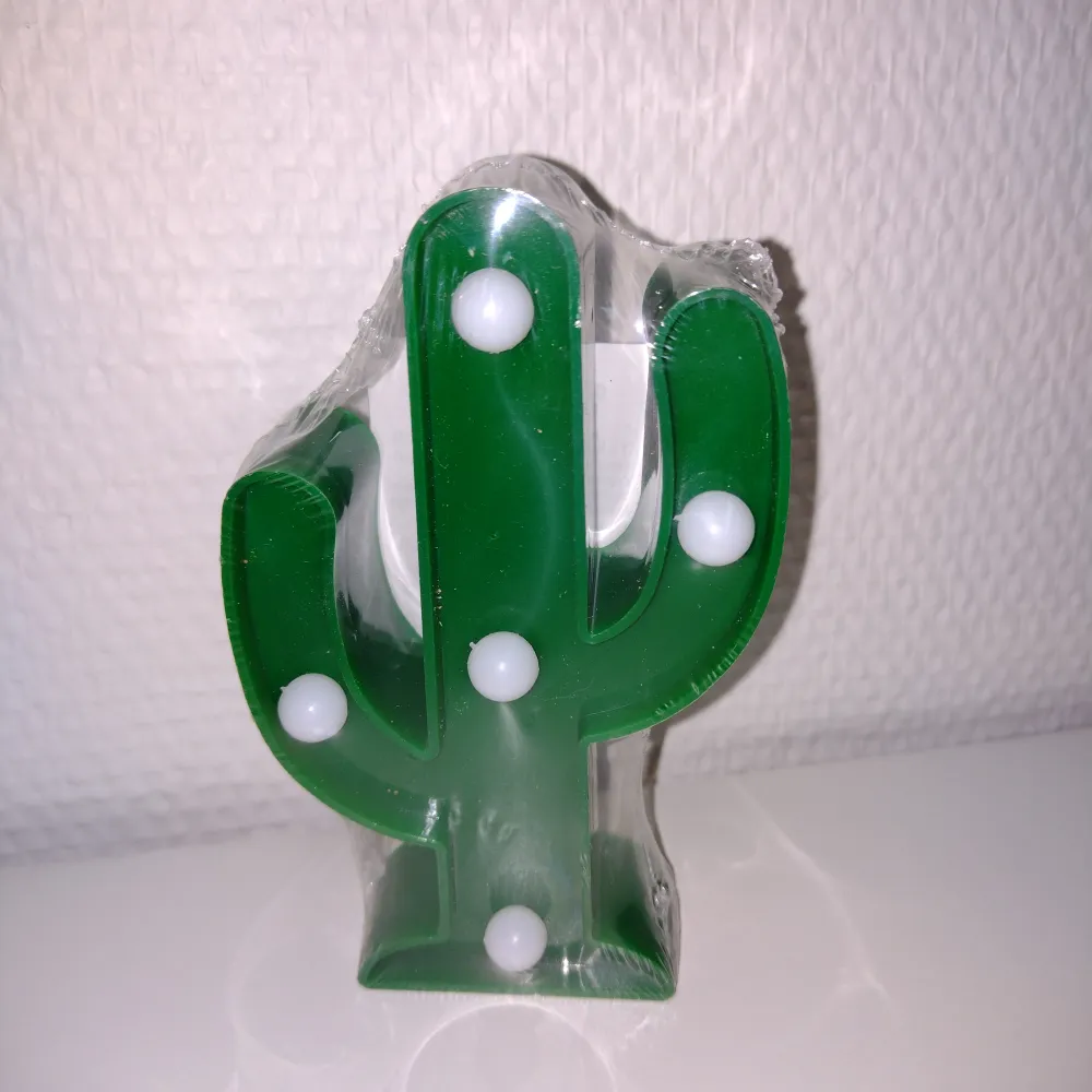 Dekorationsbelysning. Grön kaktus, ca 12 cm hög. Fem små led-lampor. Batterier medföljer. Oanvänd och inplastad.. Övrigt.