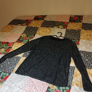 Schlager - En glittrig tröja med silver nyans, kul att ha på likaså komma användning till fest eller nånting annat för sig.