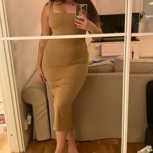 Long nude klänning  - Brun, tight, square neck klänning med slit på baksidan. Oanvänd.  