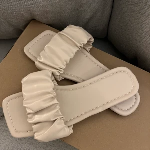 Tofflor  - Smutsrosa/beige tofflor i skinn/ läder liknande, aldrig använda, storlek 37, säljer för 70kr