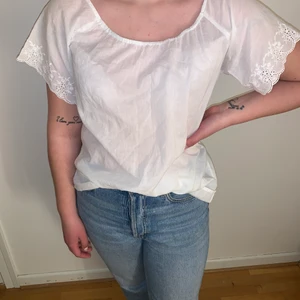 Vit blus - Luftig bus med spets detaljer. Kan användas både som off shoulder eller traditionellt tack vare resor i axlarna.